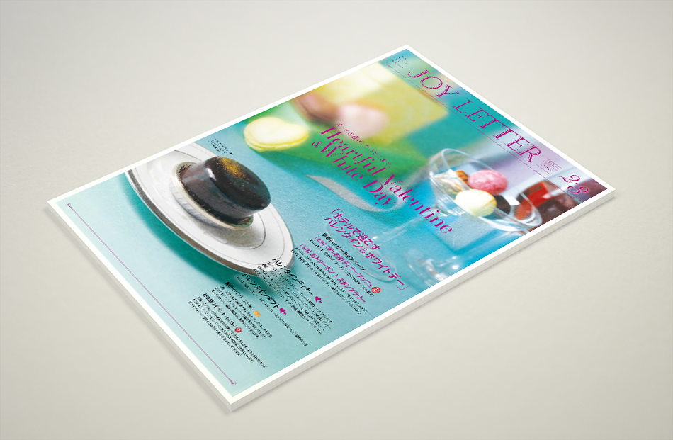 タブロイド版フリーペーパー『JOY LETTER』の表紙デザイン。バレンタインとホワイトデーを特集した号で、青と緑の背景にチョコレートやカラフルなマカロンが並ぶ。タイトルはピンクと紫のグラデーションで、華やかな印象を演出。『ホテルで過ごすバレンタイン＆ホワイトデー』というキャッチコピーが目を引く。定期刊行される情報誌で、季節ごとの特集が掲載されている。