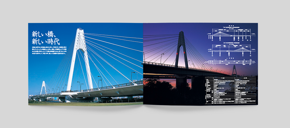 大師橋架替え工事の竣工記念パンフレットの見開きページ。左ページには青空の下にそびえ立つ新しい大師橋の主塔とケーブルが映し出され、『新しい橋、新しい時代』のキャッチコピーが記載。右ページには、夕景の大師橋と橋梁の設計図・構造図が掲載されており、技術的な詳細を視覚的に説明している。