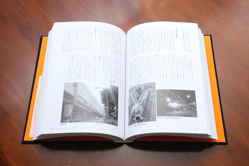 工事誌の開いたページの様子。橋梁建設の歴史や施工プロセスが詳細に記載され、モノクロ写真とともに紹介されている。上質な製本仕様で、長期保存に適した設計。企業の工事記録や技術継承のための重要なドキュメント。