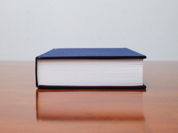 厚みのある工事誌の側面写真。青いハードカバーで製本され、数百ページに及ぶ詳細な記録が収められている。企業の工事記録や技術継承のためのアーカイブ書籍として設計され、長期保存に適した仕様。