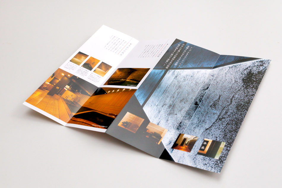 デザイナーズ銭湯のリーフレット。シックでモダンなデザインの折りたたみパンフレットが開かれ、館内の写真や設備の紹介が掲載されている。高級感のあるインテリアや落ち着いた雰囲気が伝わる構成。