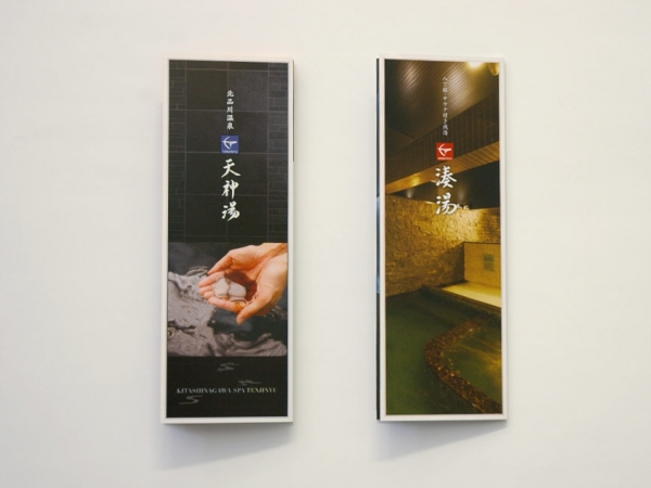 デザイナーズ銭湯『天神湯』と『湊湯』のリーフレット。黒を基調としたシックなデザインの天神湯パンフレットには、温泉の湯を手にすくう写真が掲載され、和モダンな雰囲気を演出。湊湯のパンフレットは、石造りの露天風呂の夜景が映し出され、落ち着いたリラックス空間をアピール。