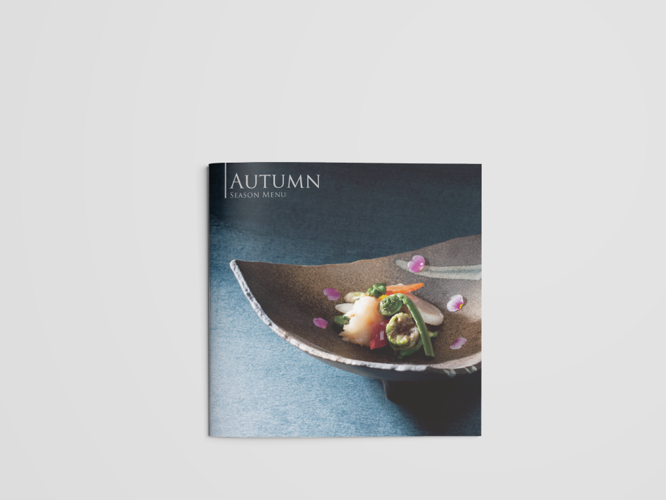 高級和食レストランの秋季限定メニューのパンフレット。表紙には、繊細な盛り付けが施された日本料理の一品が、美しい陶器の器に盛られている。山菜や海鮮、彩り豊かな野菜が使用され、周囲には食用花びらが散りばめられた上品な演出。シンプルで洗練されたデザインのタイトル『AUTUMN SEASON MENU』が左上に配置され、落ち着いた和の雰囲気を醸し出している。